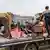 Nach dem israelischen Luftangriff in Khan Junis: Männer, Frauen und Kinder auf der Ladefläche eines LKW vor den Betonskeletten mehrerer Häuser