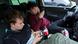 Two teens sit in a car and stare into their cellphones Two teens sit in a car and stare into their cellphones