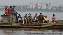 In this photo taken Monday Aug. 30, 2010, North Koreans onboard a boat float past along the swollen Yalu river near North Korea's Siniuju town across from the Chinese border town of Dandong, China's northeast Liaoning province. After Kim Jong Il's safe return, North Korea confirmed what for days had been clear: the Dear Leader was on a not-so-secret trip to northeastern China. (AP Photo) ** CHINA OUT **