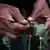 Close up of a man's hands pressing a small wooden stick into a poppy flower