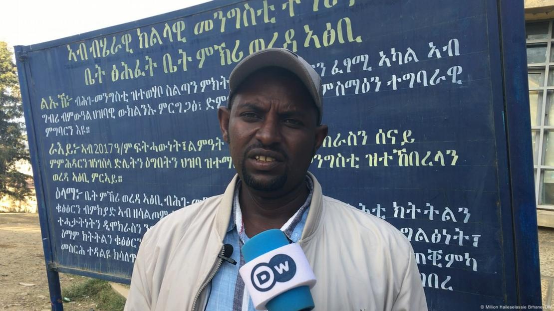 Atsibi District Administrator Mezgebe Girmay speaks to reporters in front of a billboard at Atsibi village