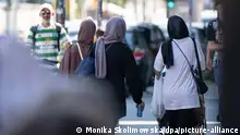 Drei Frauen mit Kopftuch gehen über eine Straße im Berliner Bezirk Neukölln