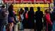 Three women wearing a Niqab stand in front of a food stand at Berlin's Hermannplatz