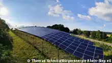 Alt-Text: Ein breites Band aus blauen Solarpanelen der Bürgerenergie Rhein-Sieg eG erstreckt sich über einer Wiese am Rand einer Schnellstraße
---
***Nur für die abgesprochene Berichterstattung zu nutzen***