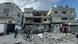 Palestinezët duke ecur pranë ndërtesave të shkatërruara në Khan Yunis Palestinezët duke ecur pranë ndërtesave të shkatërruara në Khan Yunis