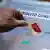 Mão coloca cédula em urna transparence com inscrição "plebiscito constitucional"