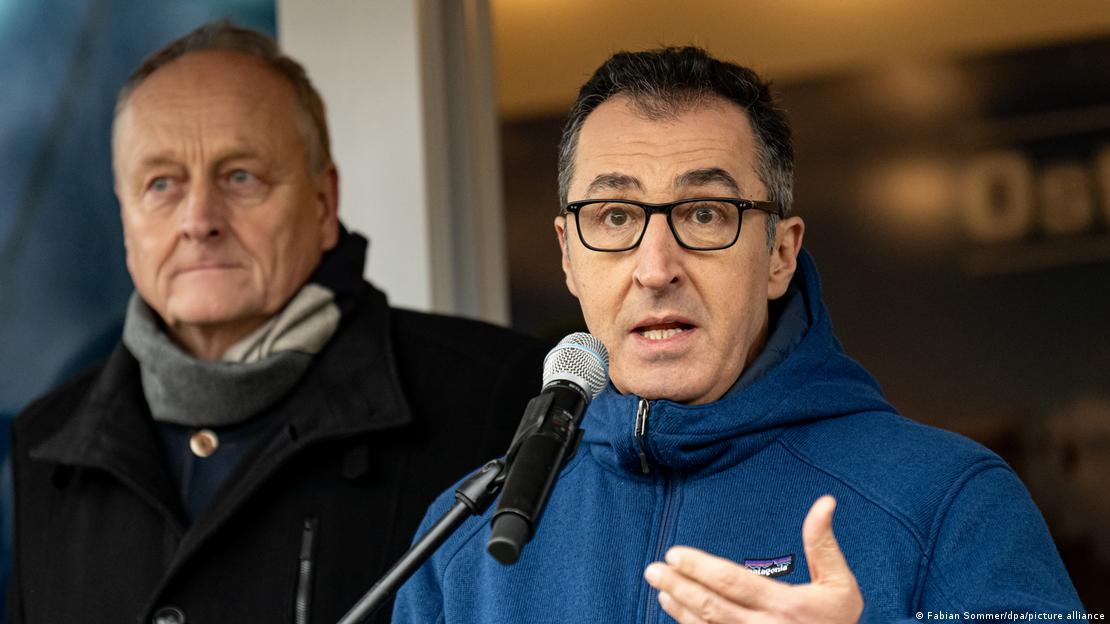 Joachim Rukwied (l), president of the German Farmers' Association, looks on as Agriculture Minister Cem Özdemir (r) addresses farmers rallying in Berlin 