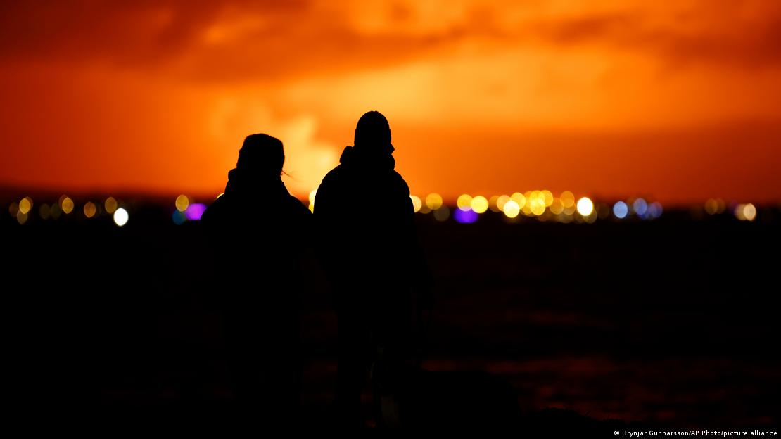 Луѓе во главниот град на Исланд, Рејкјавик го набљудуваат осветленото ноќно небо над блискиот полуостров Рејкјанес каде по повеќенеделна интензивна сеизмичка активност еруптираше тамошниот вулкан.