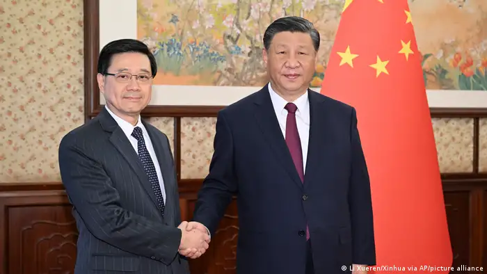2023年12月18日，在新华社发布的这张照片中，中国国家主席习近平（右）与来访的香港行政长官李家超握手。