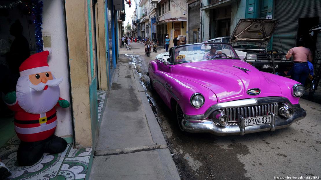 Un Papá Noel inflado y un auto antiguo en una calle de La Habana.
