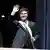 O presidente argentino Javier Milei acena e sorri enquanto ostenta a faixa presidencial