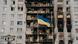 A Ukrainian flag in front of a burnt down apartment building A Ukrainian flag in front of a burnt down apartment building
