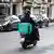 Homem dirigindo moto com mochila de aplicativo de entrega em rua na Europa