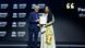 Mujer vestida de largo recibe premio de manos de hombre con traje.