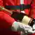 Stock photo: Close-up of the torso of a man wearing a Santa Claus costume cradling a bottle of champagne in his arms. 