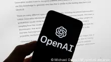 FILE - The OpenAI logo is seen on a mobile phone in front of a computer screen displaying output from ChatGPT, March 21, 2023, in Boston. The U.S. Federal Trade Commission has launched an investigation into ChatGPT creator OpenAI and whether the artificial intelligence company violated consumer protection laws by scraping public data and publishing false information through its chatbot, according to reports in the Washington Post and the New York Times. (AP Photo/Michael Dwyer, File)