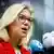Sigrid Kaag speaks to the press to announce leaving politics, dressed in red and wearing glasses, with blonde hair
