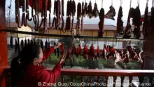 A woman hangs up the preserved ham in her new house at the quake-hit Xiaoyudong town in Pengzhou in southwest China's Sichuan province on Sunday, Dec. 27, 2009. Pengzhou plans to invest 83.2 billion yuan in the quake zone reconstruction project in the next three years. More than 80,000 people were killed in last year's May 12 earthquake.(Photo By Zheng Duo/Color China Photo/AP Images)