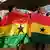 Two Ghanaian women hold Ghanaian flags