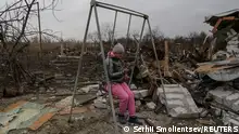 01.01.2024, A girl uses her mobile phone while she sits on a swing at a compound of residential houses heavily damaged during a Russian drone strike, amid Russia's attack on Ukraine, in Odesa, Ukraine January 1, 2024. REUTERS/Serhii Smolientsev