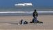 Three migrants on a beach with a ferry in the background Three migrants on a beach with a ferry in the background