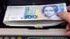 A hand placing 100-mark-bills into a counting-machine at the bank A hand placing 100-mark-bills into a counting-machine at the bank