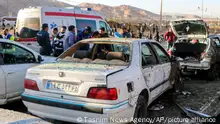 People stay next to destroyed cars after an explosion in Kerman, Iran, Wednesday, Jan. 3, 2024. Iran says bomb blasts at an event honoring a prominent Iranian general slain in a U.S. airstrike in 2020 have killed at least 103 people and wounded 188 others. (Tasnim News Agency via AP)