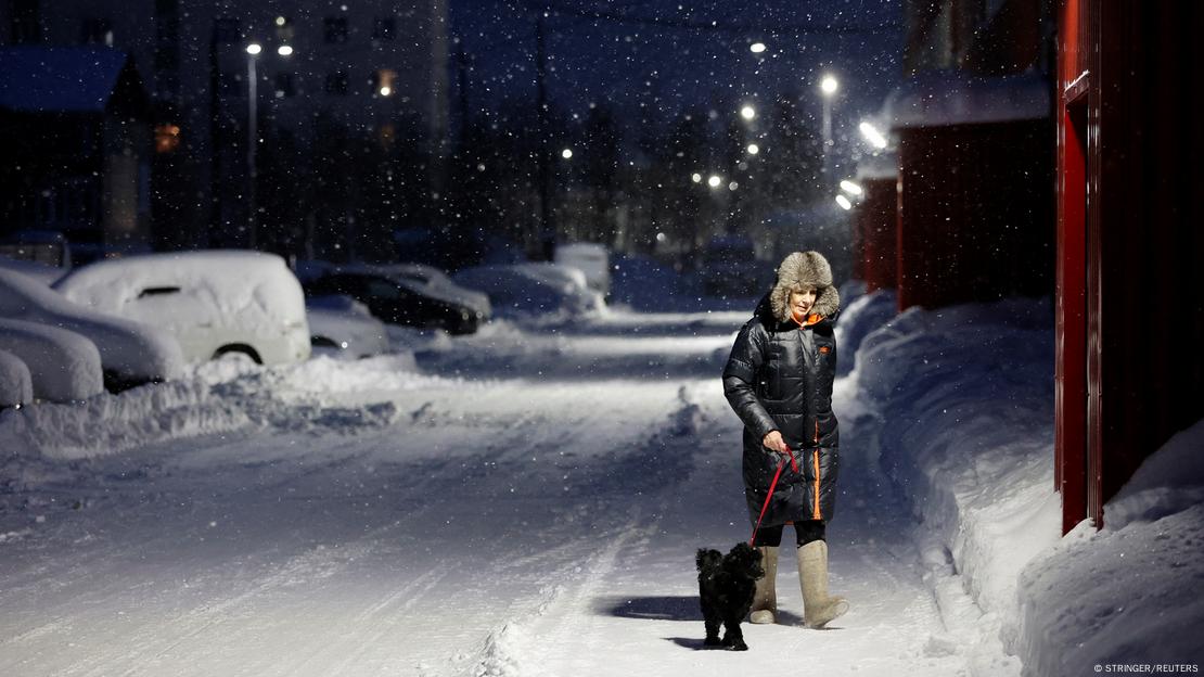 A woman walks her dog in the Russian settlement of Kharp