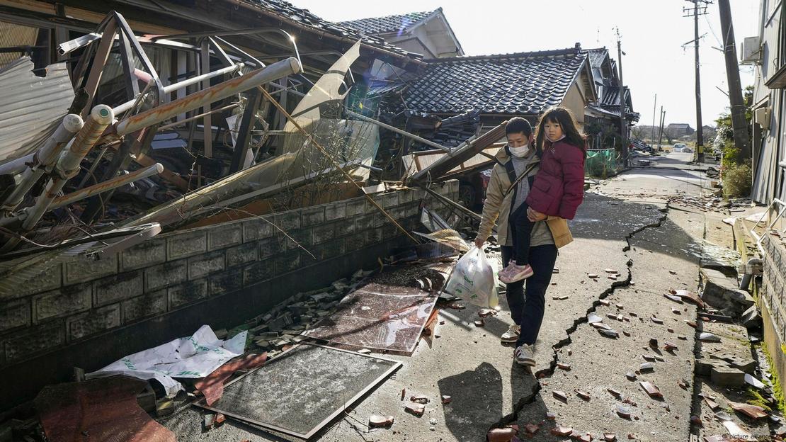 Un hombre con una niña camina entre casas derrumbadas en Suzu, prefectura de Ishikawa. Un hombre con una niña camina entre casas derrumbadas en Suzu, prefectura de Ishikawa.