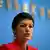 Sahra Wagenknecht with her lips pursed while speaking in front of a blue background at a press conference in Berlin