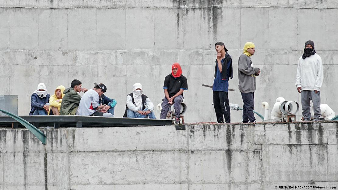 Prisioneiros sobem no muro de em uma penitenciária no Equador durante revolta