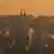 Fumaça sobe das chaminés dos telhados de Praga durante o nascer do sol