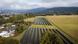 Drone image of 20 rows of solar panels in a field. In the background are houses, trees and hills, Ladek-Zdroj, Poland, September 25, 2023 Drone image of 20 rows of solar panels in a field. In the background are houses, trees and hills, Ladek-Zdroj, Poland, September 25, 2023