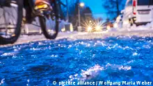 Deutschland, München, 17. Januar 2024, Eisregen morgens um 7:45 Uhr, extrem gefährliche Straßenglätte, Radfahrer und Autofahrer in einer Nebenstraße in München-Waldperlach, dunkel, Temperaturen um die -1 Grad, Winter, Bayern,