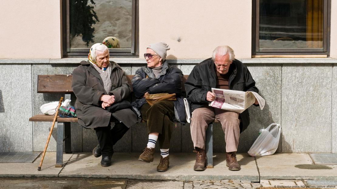 Bankta oturan, sohbet eden ve gazete okuyan yaşlı insanlar