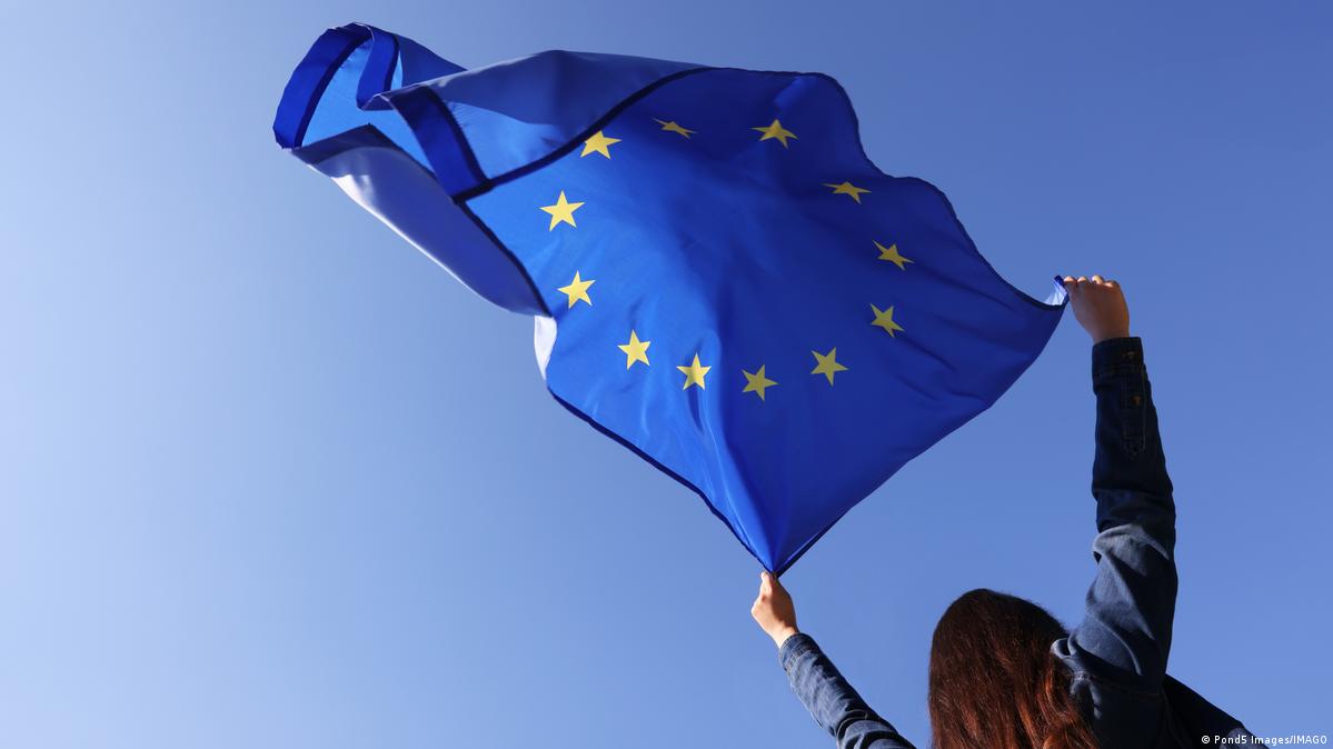 Eine Frau lässt eine EU-Fahne in der Luft wehen.