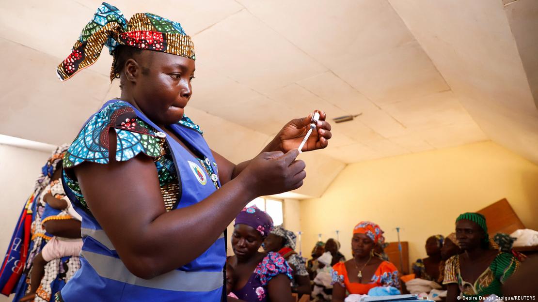 Mulher com roupa típica de países africanos manipula seringa e ampola de vacina