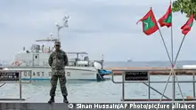 A military person stands guard at a boat jetty next to Maldivian flags erected ahead of Republic Day in Male, Maldives, Thursday, Nov. 5, 2015. Maldives' Parliament voted overwhelmingly on Thursday to impeach the country's vice president, who will be charged with terrorism for plotting to kill the president, a minister said. The president, who was not hurt in the blast, has declared a state of emergency, saying the explosion and subsequent discovery of arms posed a threat to national security. (AP Photo/Sinan Hussain)