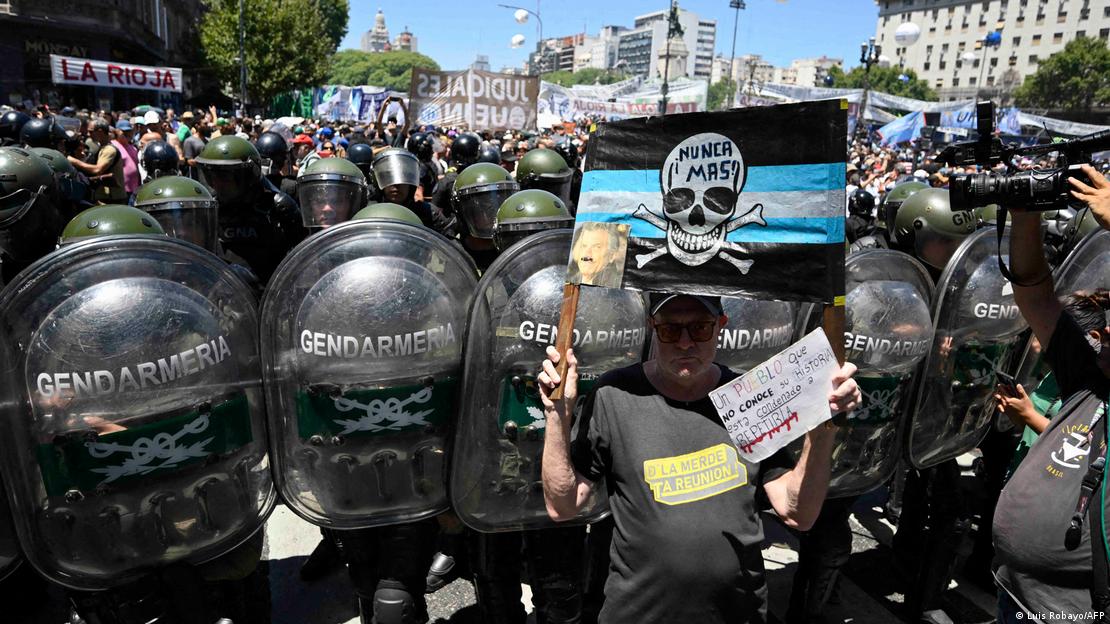 A man protesting outside the Argentine Congress with police standing in riot gear behind him