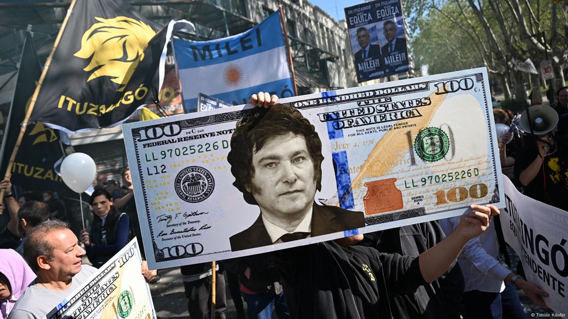 Manifestantes muestran un billete gigante de dólar con la cara de Milei.