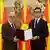 Talat Xhaferi (left) and President Stevo Pendarovski (right) hold an official document between them while standing in front of a mosaic and three North Macedonian flags, Skopje, North Macedonia, January 26, 2024