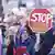 A man in a group of protesters holds up a protest sign, a red stop sign with the words "Stop Nazis"