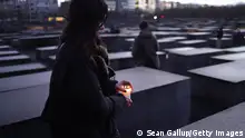 BERLIN, GERMANY - JANUARY 26: A local woman prepares to lay a candle among stelae at the Memorial to the Murdered Jews of Europe, also called the Holocaust Memorial, on the eve of International Holocaust Remembrance Day on January 26, 2024 in Berlin, Germany. Tomorrow will be the 79th anniversary of the liberation of the Auschwitz concentration camp, the biggest of the many concentration camps used by the Nazis during World War II to enslave and exterminate millions of Jews, political opponents, Roma and other Nazi-deemed undesirables. (Photo by Sean Gallup/Getty Images)