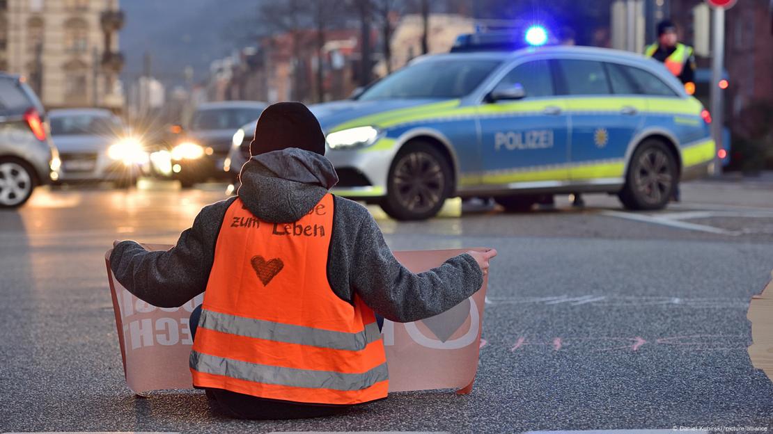 Jemand sitz auf der Straße und blockiert sie