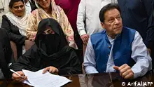 Pakistan's former Prime Minister, Imran Khan (R) along with his wife Bushra Bibi (L) looks on as he signs surety bonds for bail in various cases, at a registrar office in the High court, in Lahore on July 17, 2023. Former Pakistan Prime Minister Imran Khan and his wife were sentenced on January 31, 2024, to 14 years in jail, local media said, after being found guilty of graft in a case involving gifts he received while premier. (Photo by Arif ALI / AFP)