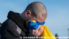 Yüzünü Ukrayna bayrağına süren bir kişi