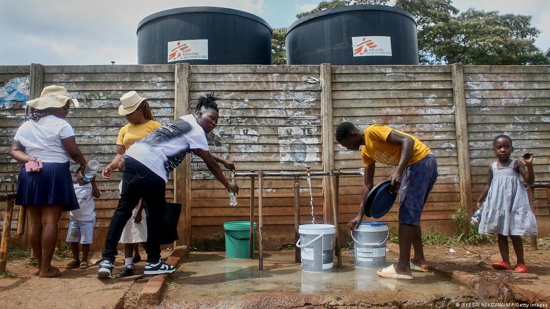 Several young people are filling up bottles and buckets with safe drinking water Several young people are filling up bottles and buckets with safe drinking water