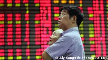 FILE PHOTO: A man stands in front of an electronic stock board in the stock market of Shanghai June 19, 2006. REUTERS/Aly Song/File Photo