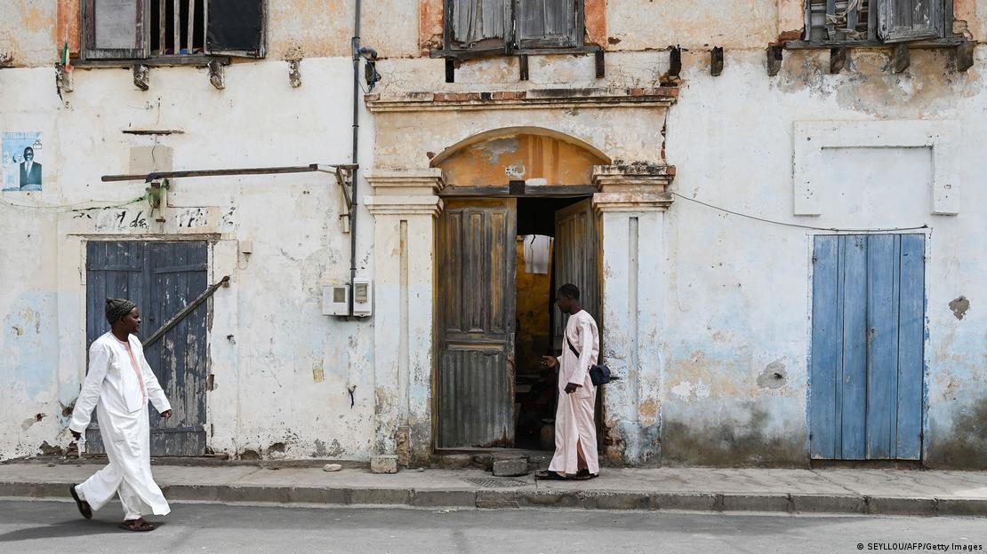Senegal | Saint-Louis - Des habitants marchent dans une rue bordée de bâtiments délabrés, à Saint-Louis, dans le nord du Sénégal Senegal | Saint-Louis - Des habitants marchent dans une rue bordée de bâtiments délabrés, à Saint-Louis, dans le nord du Sénégal