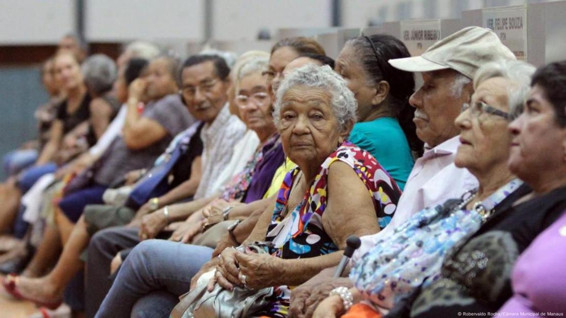 Idosos aguardam em fila para acessar serviço público. 